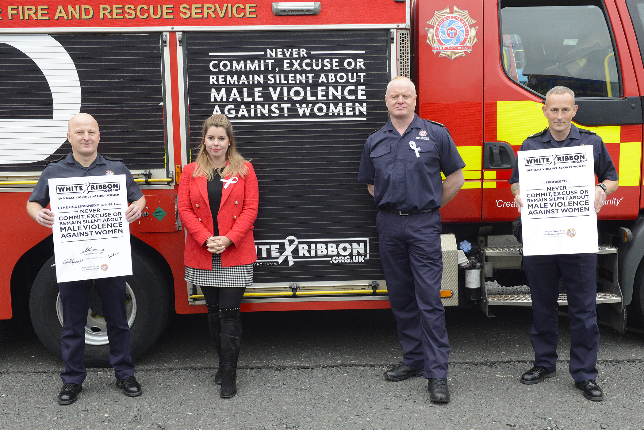 (Left to Right) Firefighter Steve Wilson, Northumbria Police and Crime Commissioner, Kim McGuinness, Chief Fire Officer Chris Lowther and Crew Manager John Webster standing in front of a TWFRS appliance sporting the White Ribbon logo.