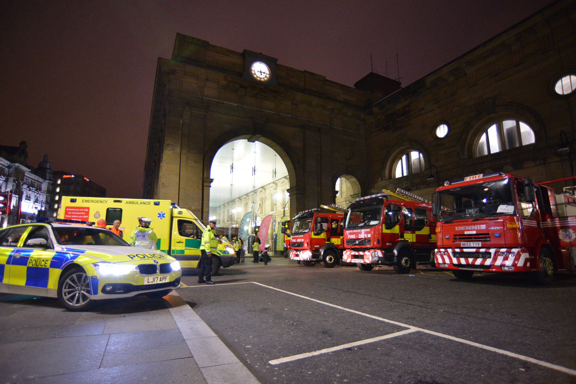 A Northumbria Police Vehicle, North East Ambulance Service Vehicle, and three Tyne and Wear Fire and Rescue Service Fire Appliances outside Newcastle Central Station.