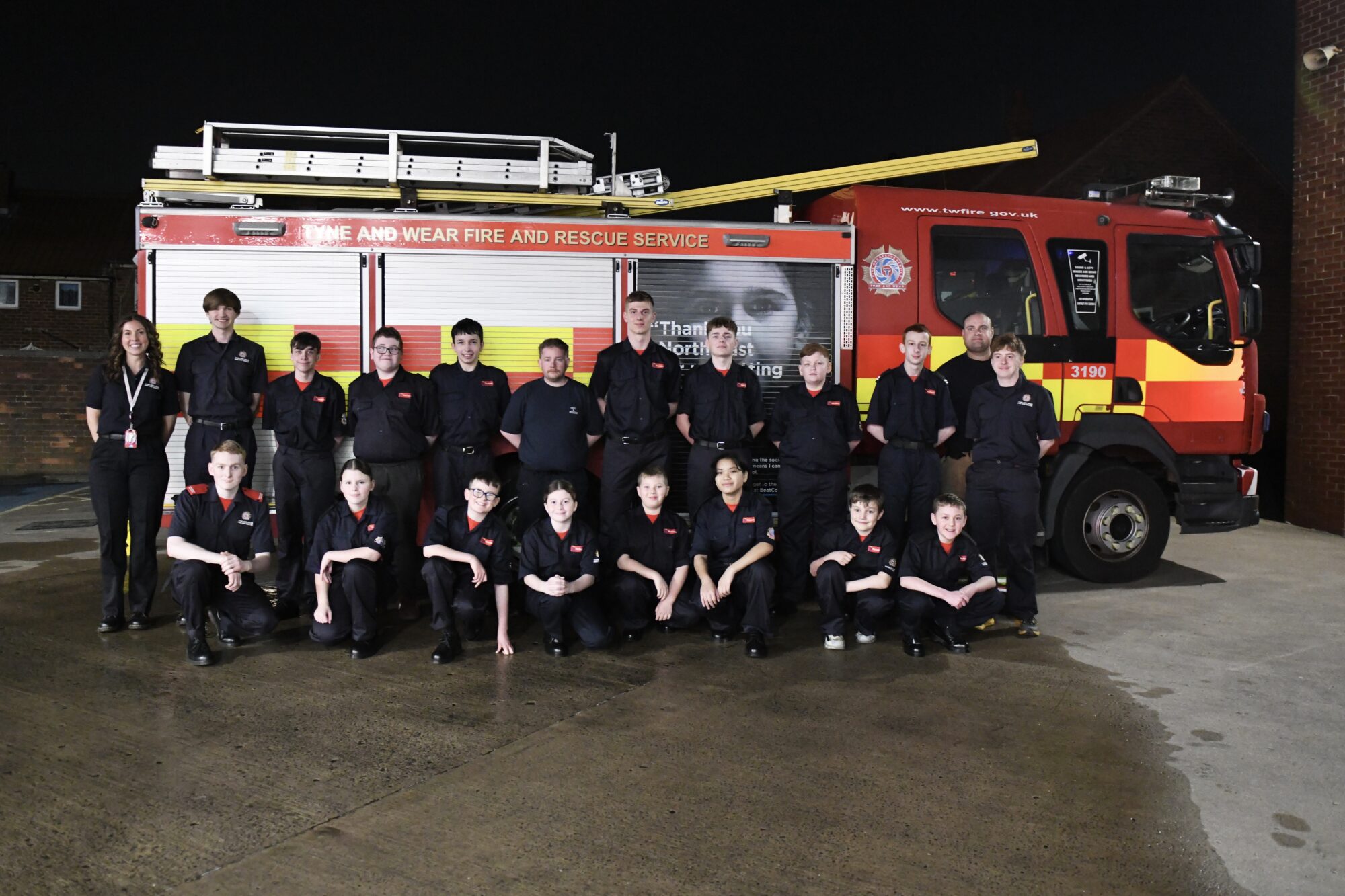 Group photo of TWFRS Fire Cadets standing in front of a fire appliance.