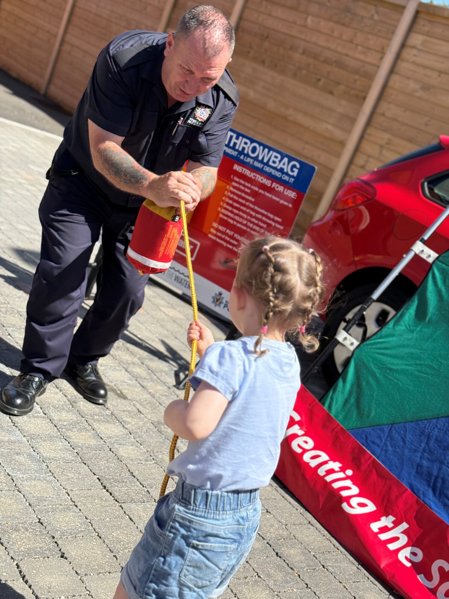 Firefighter demonstrating water safety throw line with small child pulling rope
