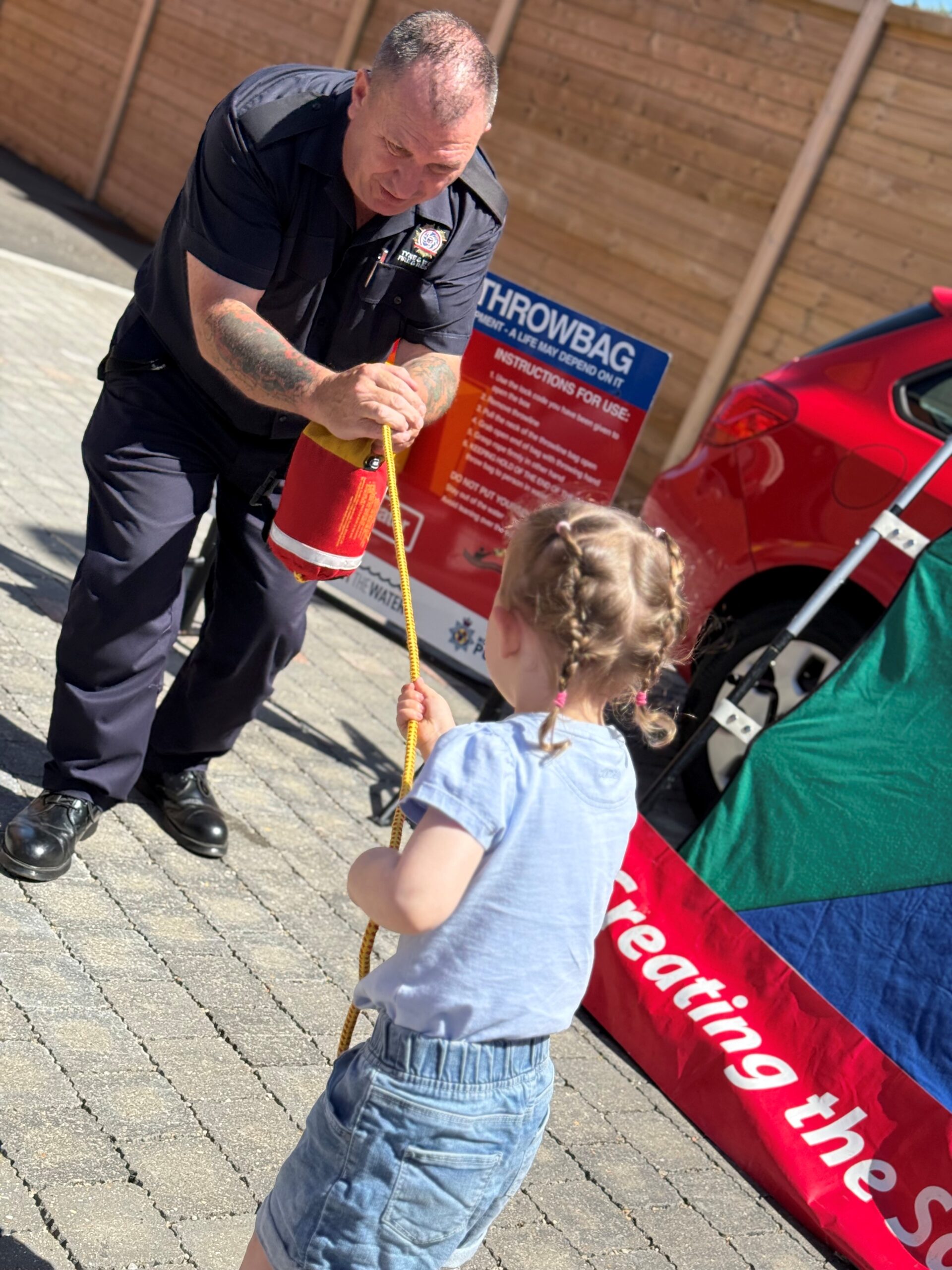 Firefighter demonstrating water safety throw line with small child pulling rope