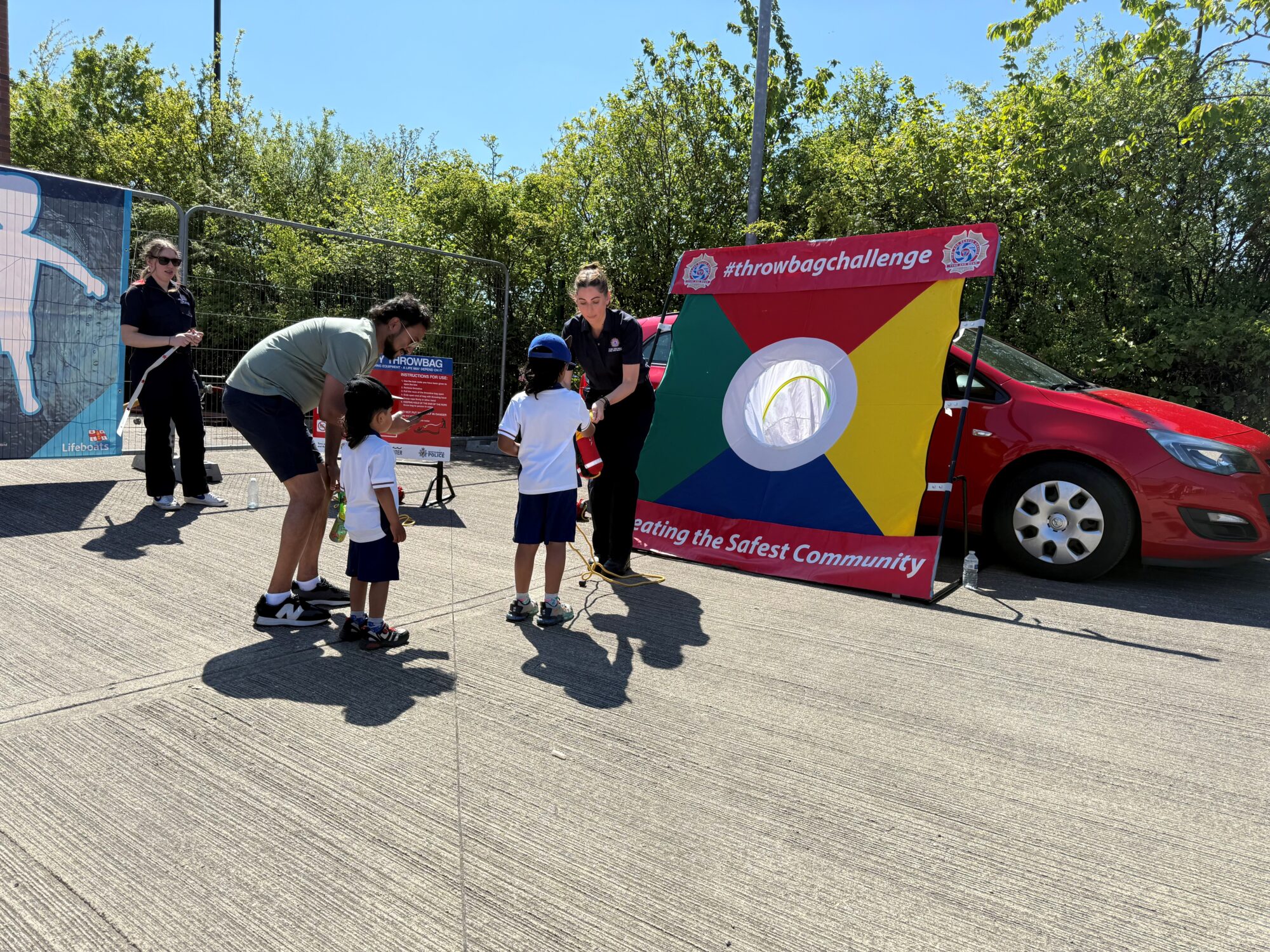 Two adults and two children engaging with a throw line board - aiming to throw the bag into the target